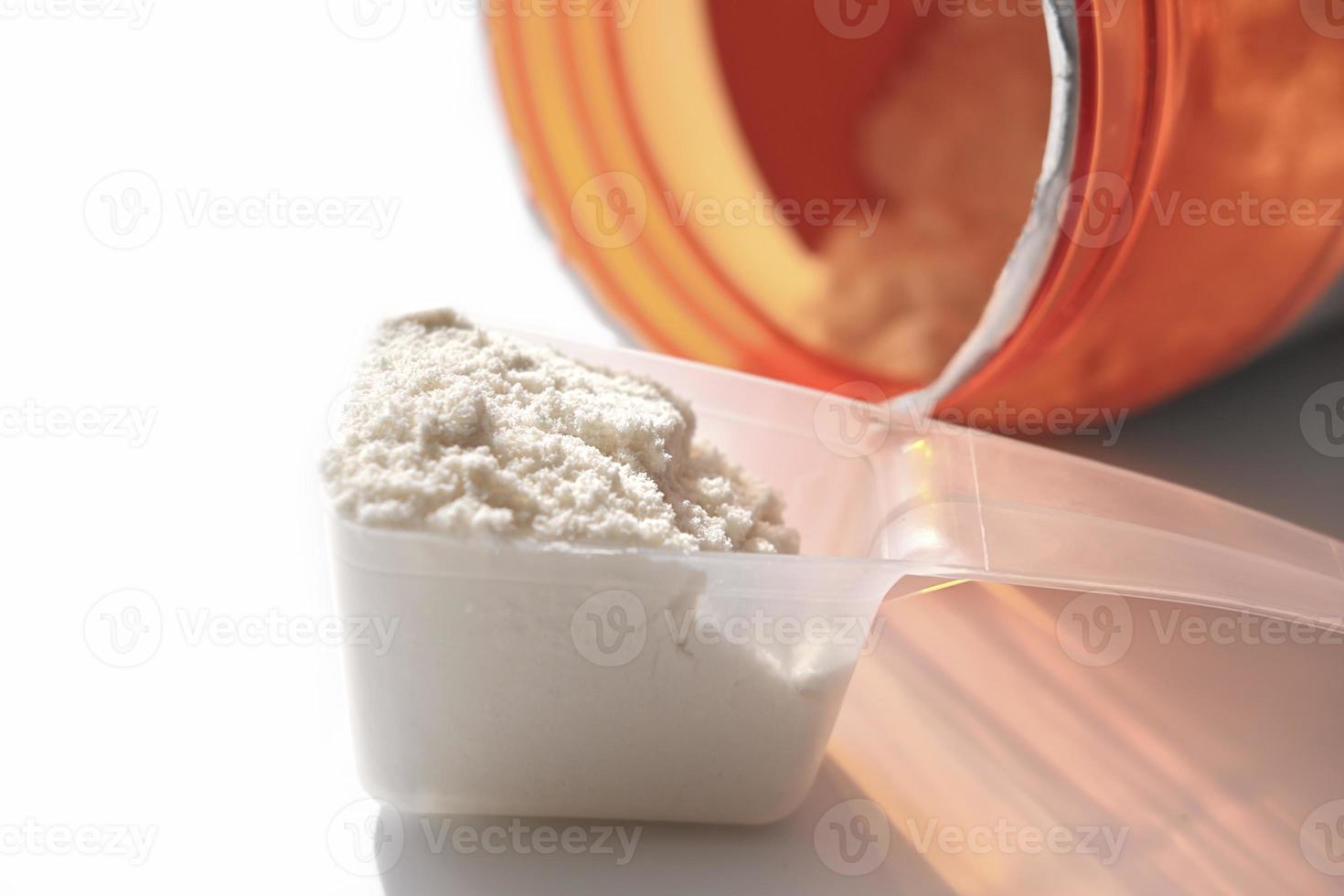 scoop of whey protein and jar with protein powder. vanilla flavored supplement for healty lifestyle, close up view photo