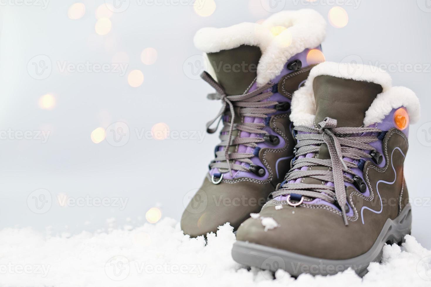Pair of woman suede grey boots on snow in winter sunny day. photo