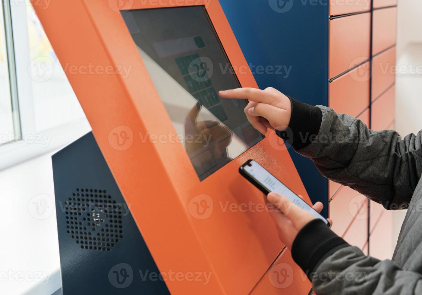 client using automated self service post terminal machine or locker to receive a parcel or to deposit the box. contactless delivery to pick up point photo