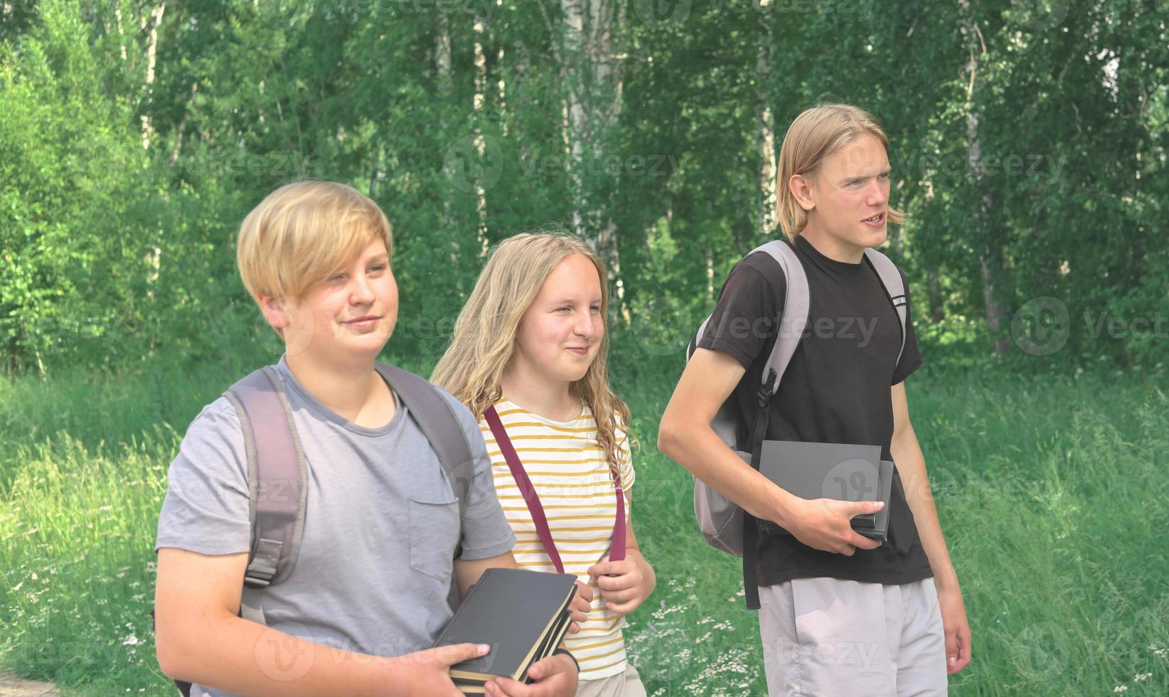portrait of a group of teenagers of various height with schoolbags and books coming to school, back to school concept. photo