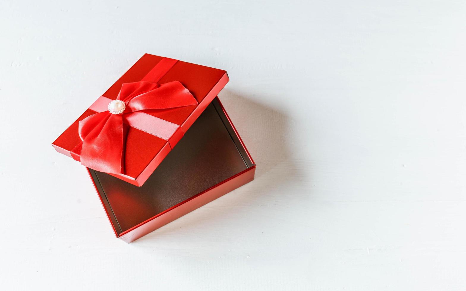 Red gift box  opened on white wooden table photo