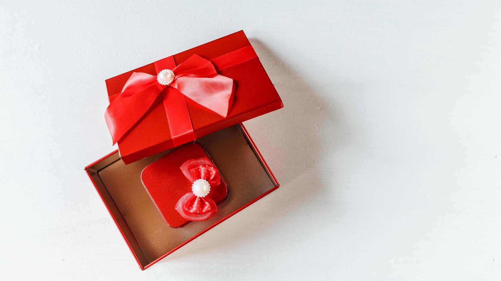 Red gift box  opened on white wooden table photo