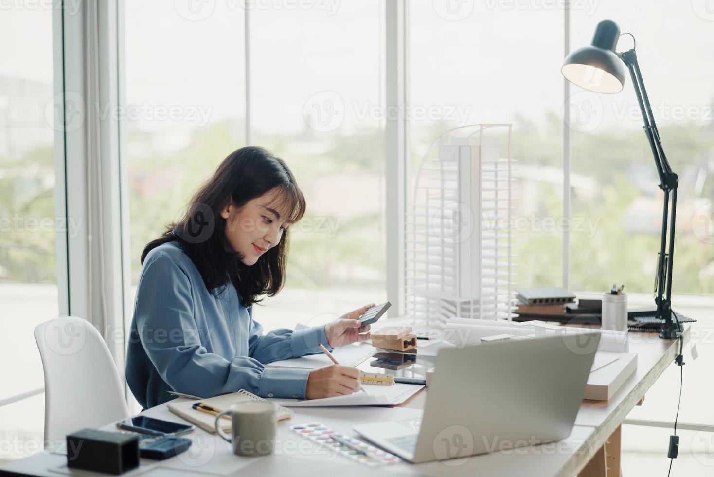 enfoque selectivo, arquitecta o ingeniera asiática que actualmente considera materiales para diseñar condominios modernos. arquitecta o ingeniera asiática sentada y analizando, diseñando proyectos en la oficina foto