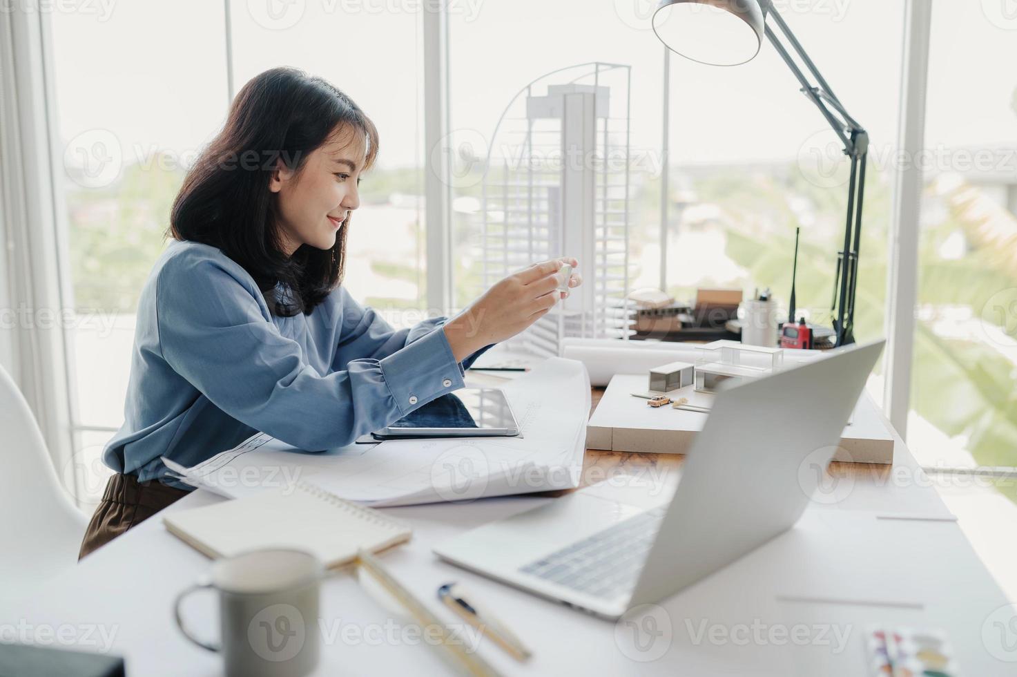 enfoque selectivo, arquitecta o ingeniera asiática que actualmente considera materiales para diseñar condominios modernos. arquitecta o ingeniera asiática sentada y analizando, diseñando proyectos en la oficina foto