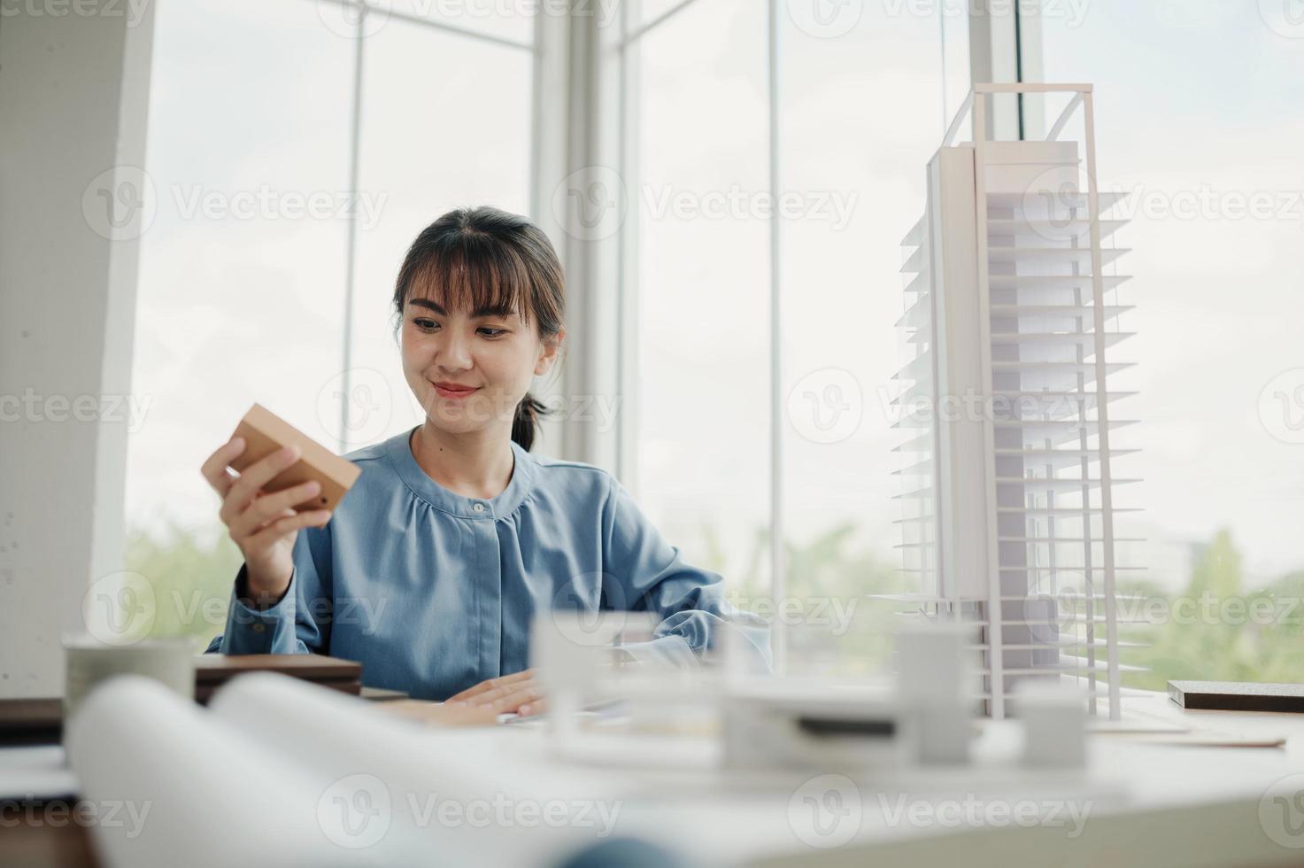 enfoque selectivo, arquitecta o ingeniera asiática que actualmente considera materiales para diseñar condominios modernos. arquitecta o ingeniera asiática sentada y analizando, diseñando proyectos en la oficina foto