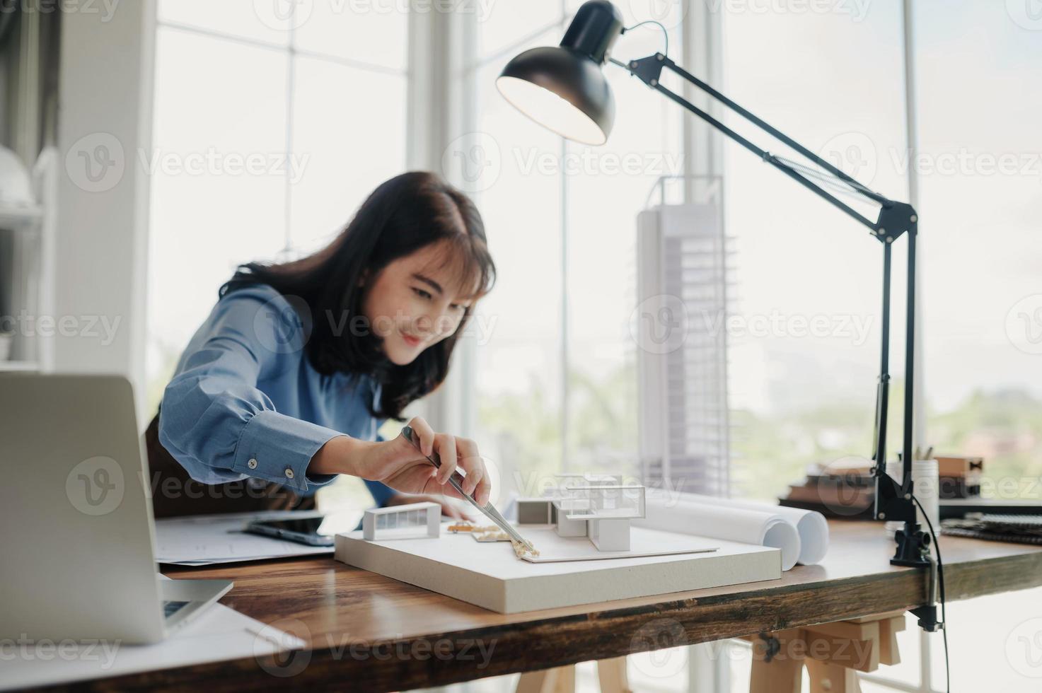 enfoque selectivo, arquitecta o ingeniera asiática que actualmente considera materiales para diseñar condominios modernos. arquitecta o ingeniera asiática sentada y analizando, diseñando proyectos en la oficina foto