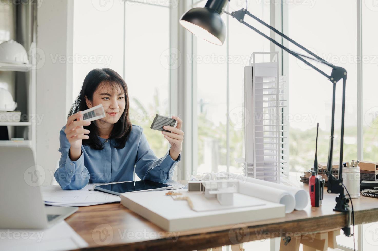 Selective focus, Asian female architect or engineer Currently considering materials for designing modern condominiums. Asian female architect or engineer Sit and analyze, design projects in the office photo