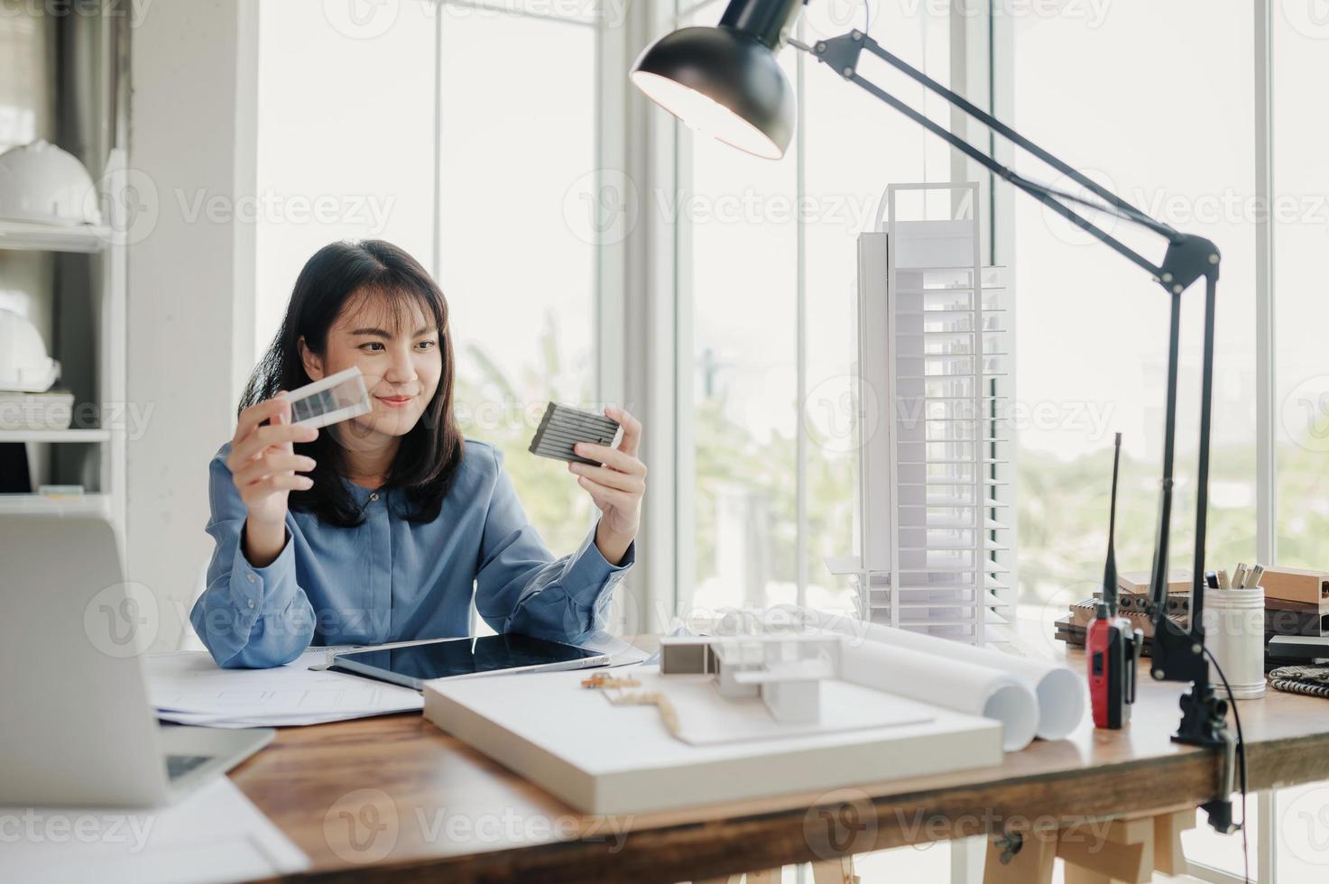 enfoque selectivo, arquitecta o ingeniera asiática que actualmente considera materiales para diseñar condominios modernos. arquitecta o ingeniera asiática sentada y analizando, diseñando proyectos en la oficina foto