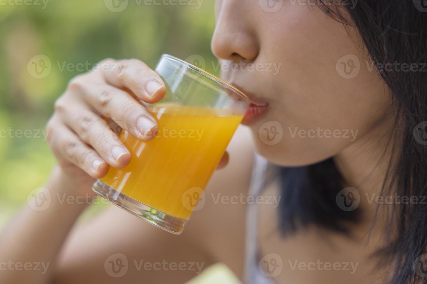 Close up of woman drink orange juice. Girl enjoy fruit juice for lunch, wellbeing diet concept. Concept of health photo