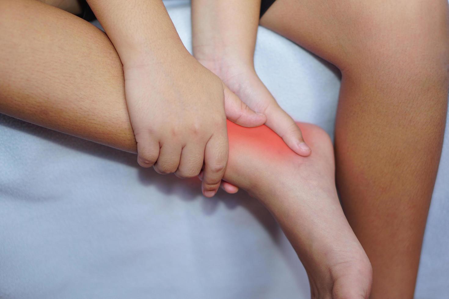 The boy touching his ankle in pain. Health and treatment concept. photo