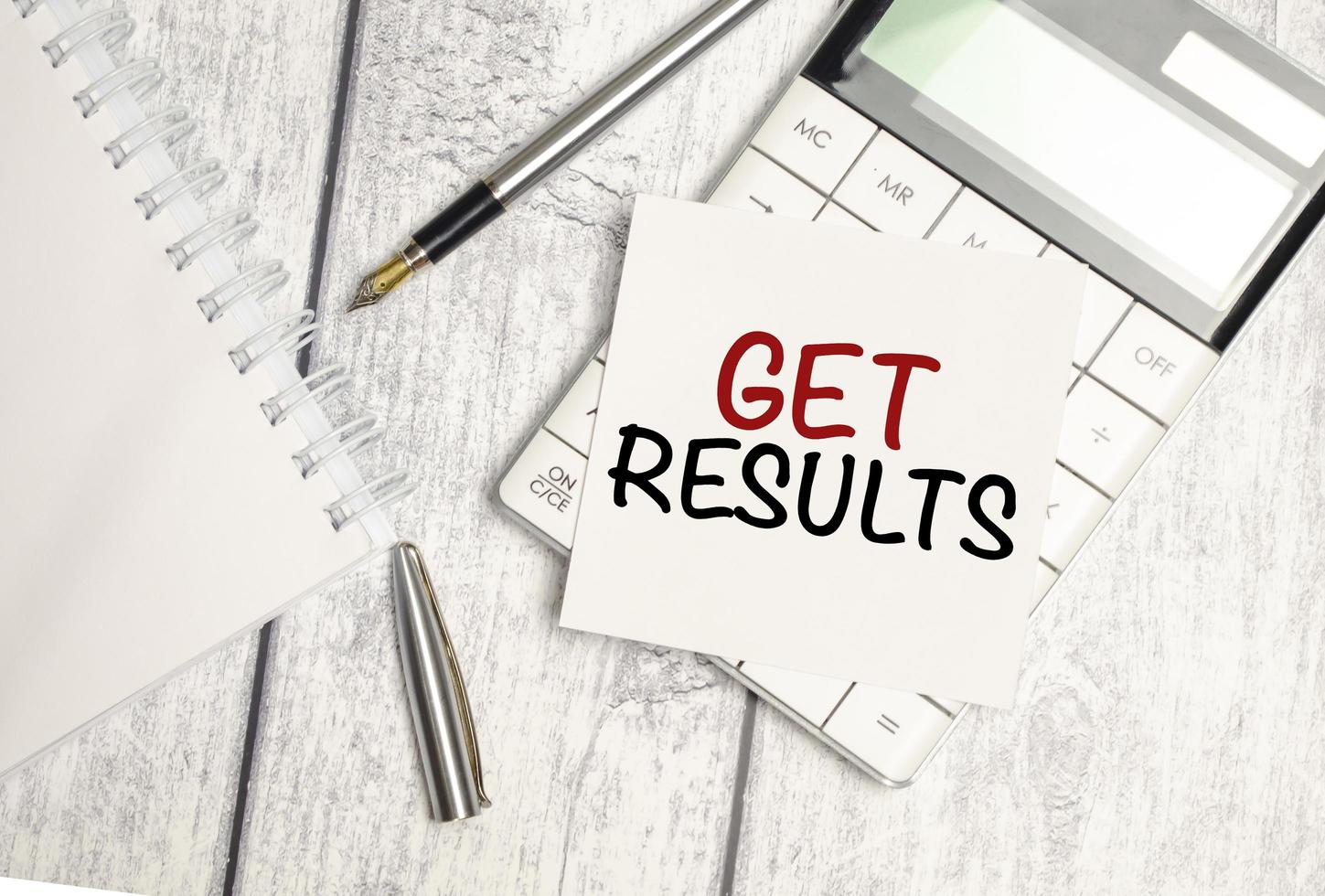 get results - text on white sticker and calculator with pen on wooden background photo