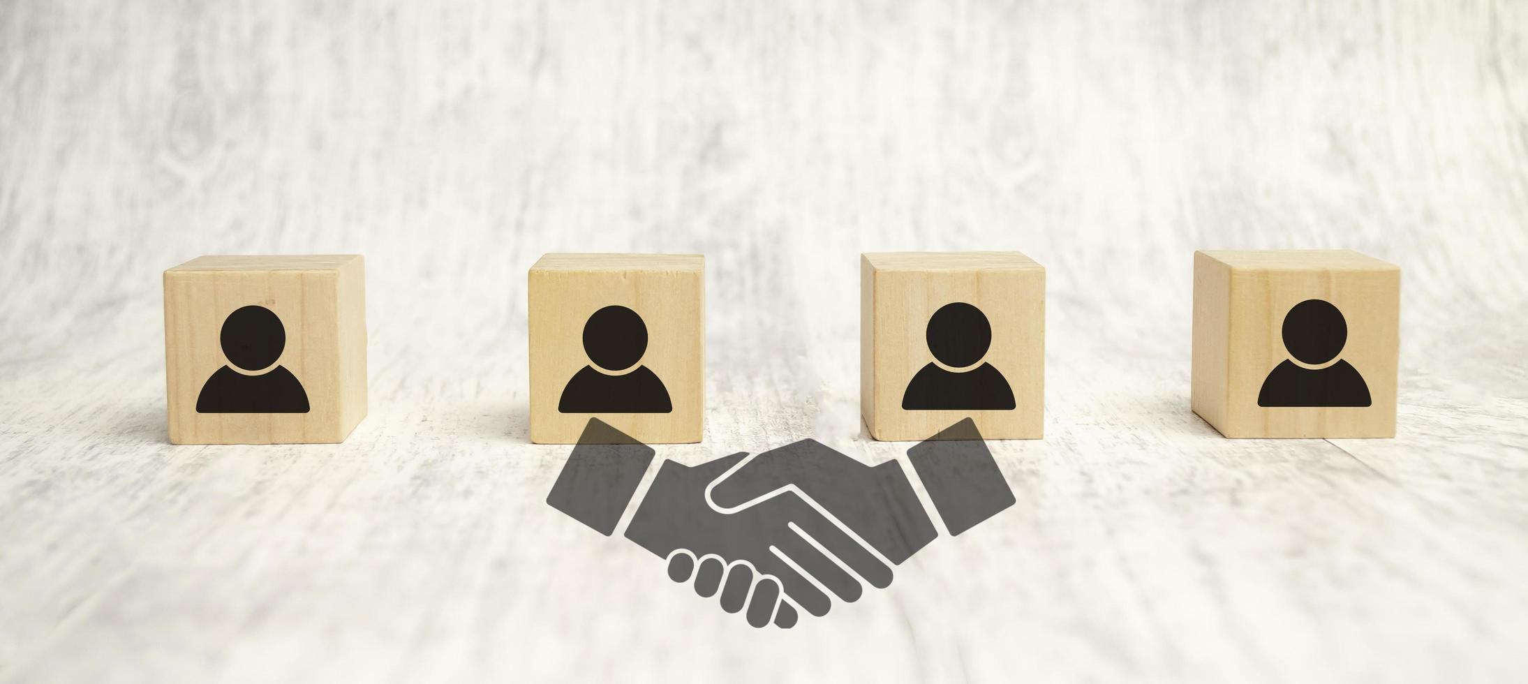 handshake icon screen on wooden cube block over employees wooden background photo