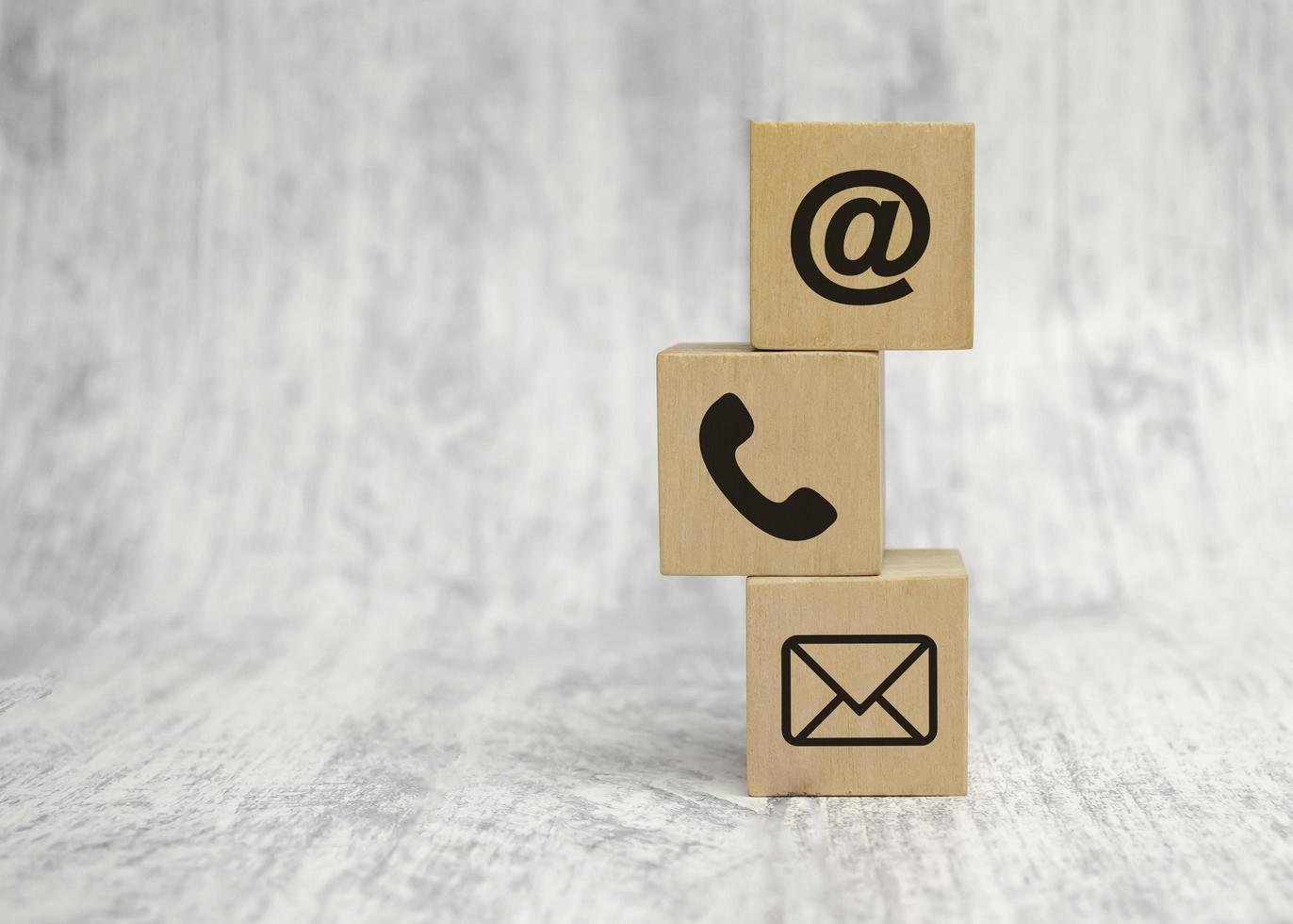 Contact us concept with wood block and symbols at, e-mail address and phone photo