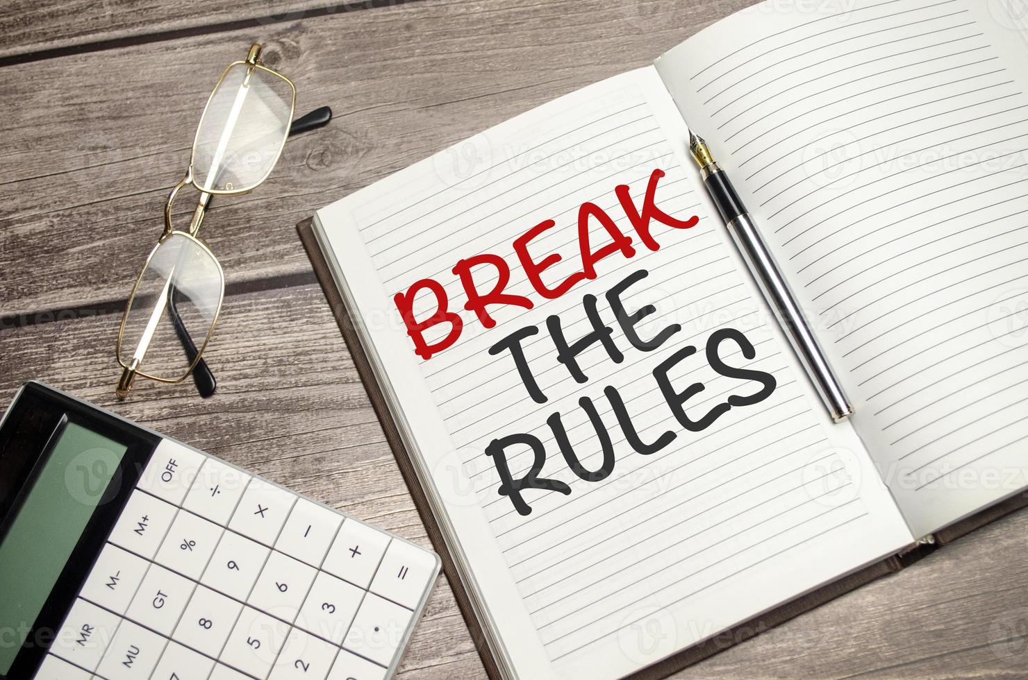 text break the rules on brown diary with calculator, glasses on wooden background photo