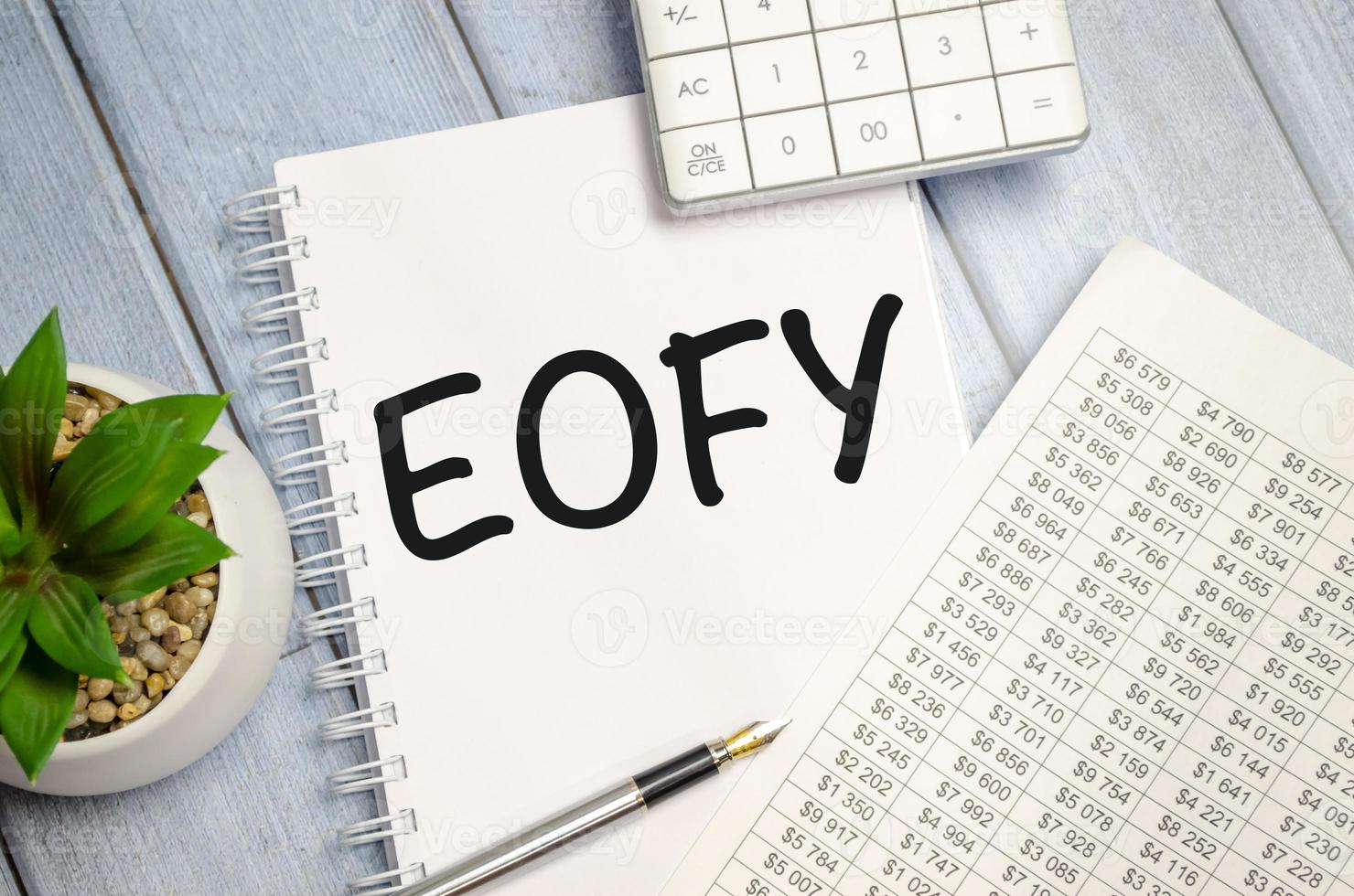 notebook over wood table background, focus on wooden blocks with letters making End of Financial Year text photo