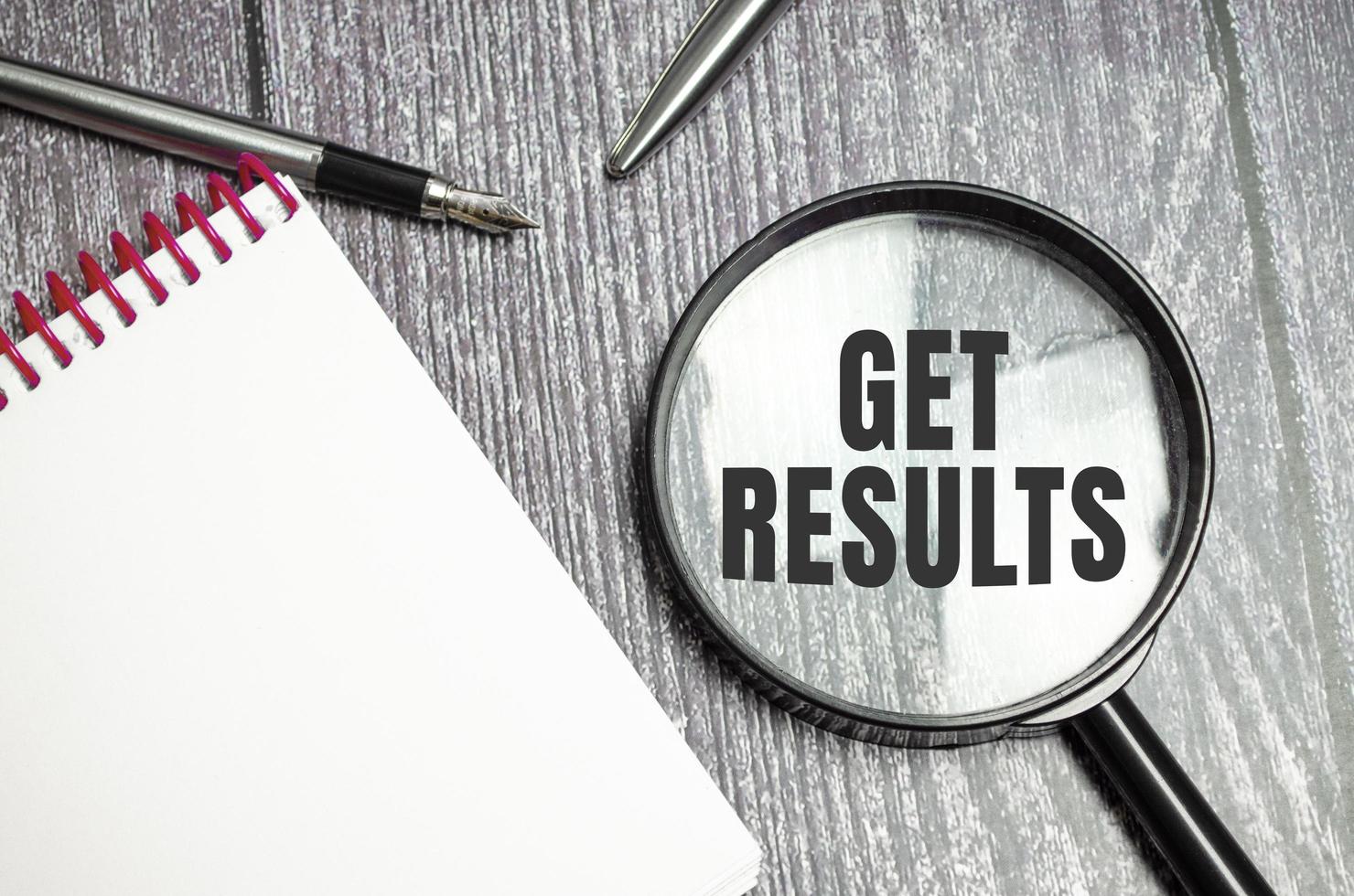 get results symbol on magnifier and pen on wooden background photo