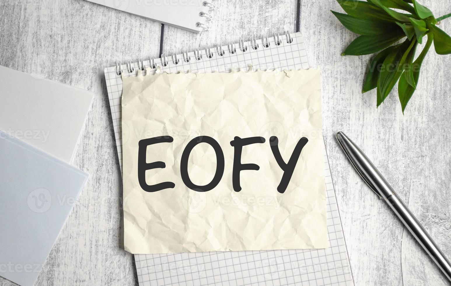 notebook over wood table background, focus on wooden blocks with letters making End of Financial Year text photo