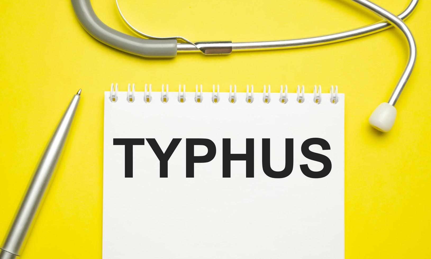 la palabra tifus escrita en un bloc de notas blanco sobre un fondo amarillo foto