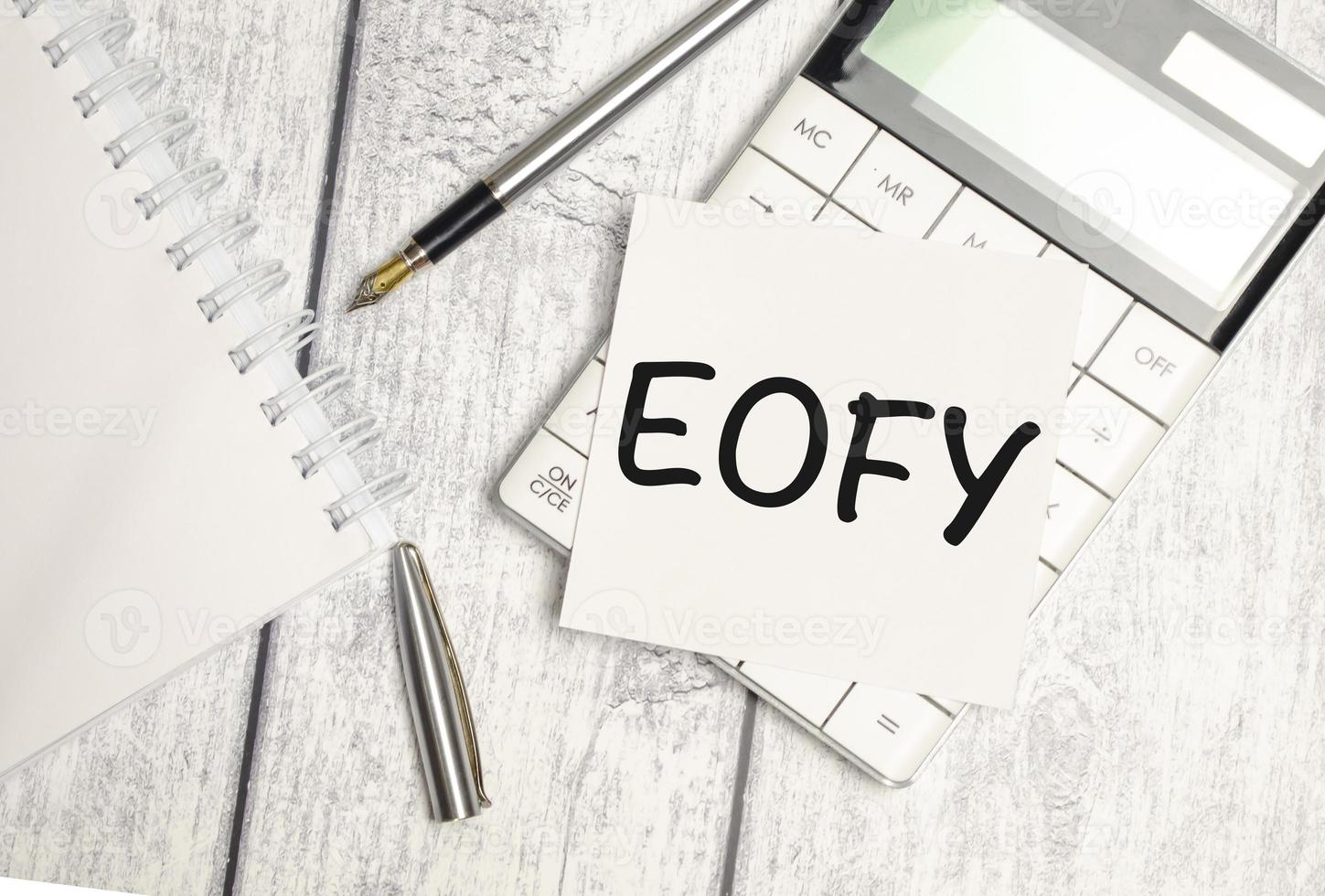 notebook over wood table background, focus on wooden blocks with letters making End of Financial Year text photo