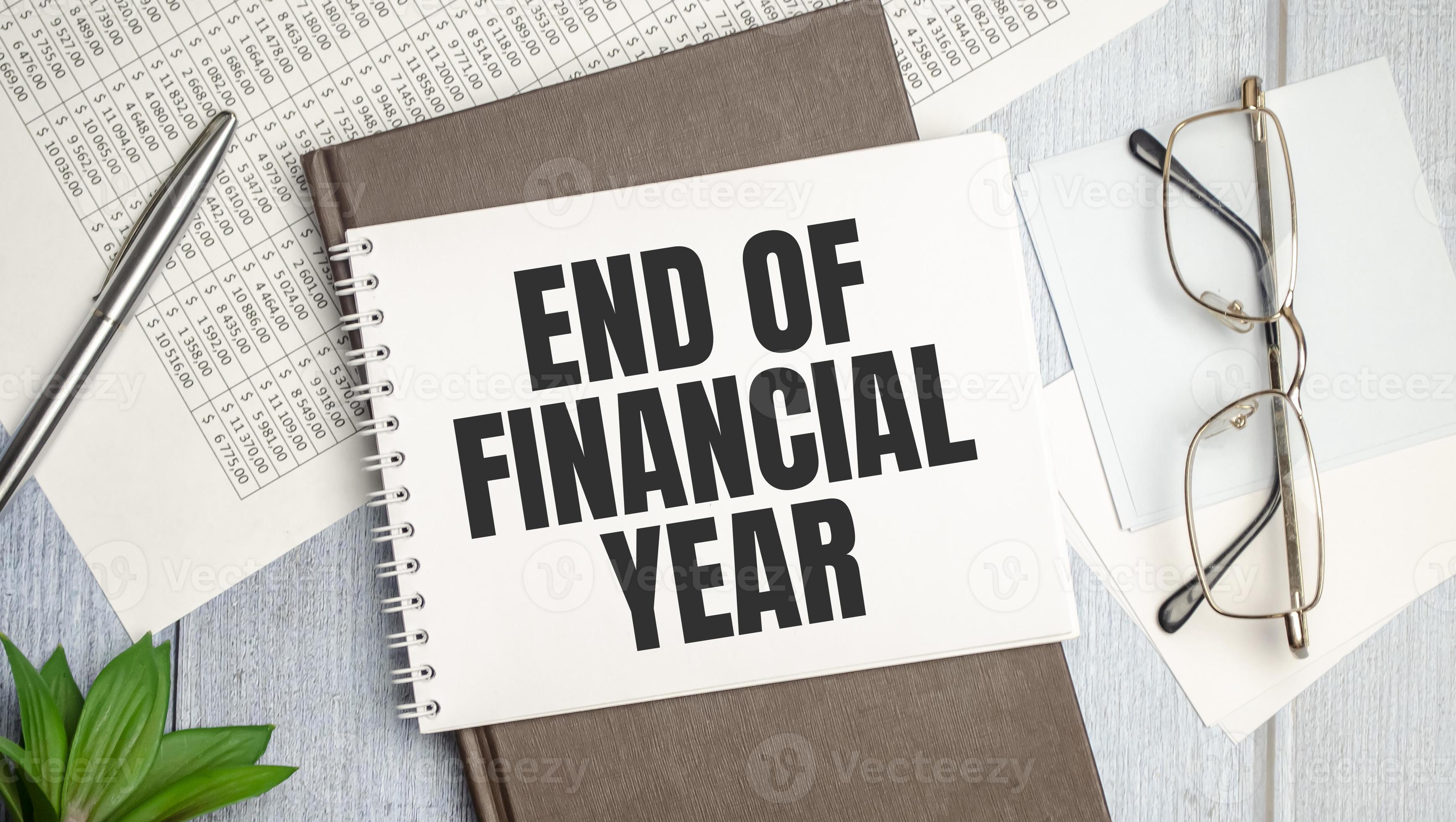Text End of Financial Year on a notebook on the diagram and charts with calculator and pen