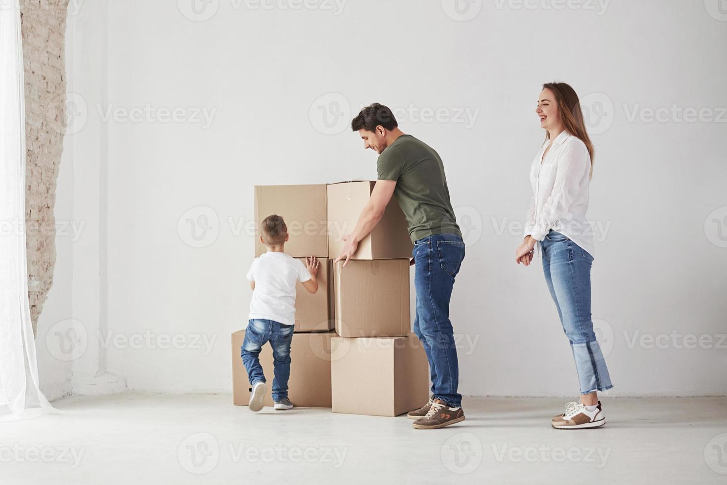 el niño ayuda a los padres. la familia tiene mudanza a una nueva casa. desempacar cajas de mudanza foto