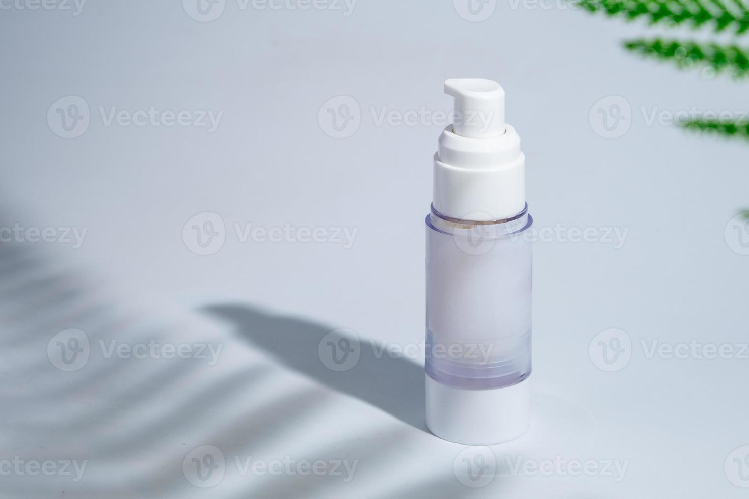 cosmetic and skin care package in a glass bottle on white background with hard or Harsh shadows and sunlight of leaves tree branch falling on wall. modern and minimal beauty product design photo