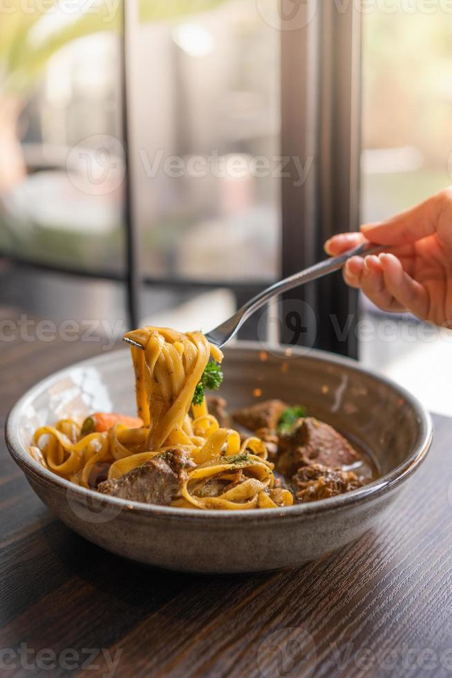 selective focus, Tagliatelle with pork stew and vegetables in a bowl served on wooden table, Spaghetti Pasta with meat. photo