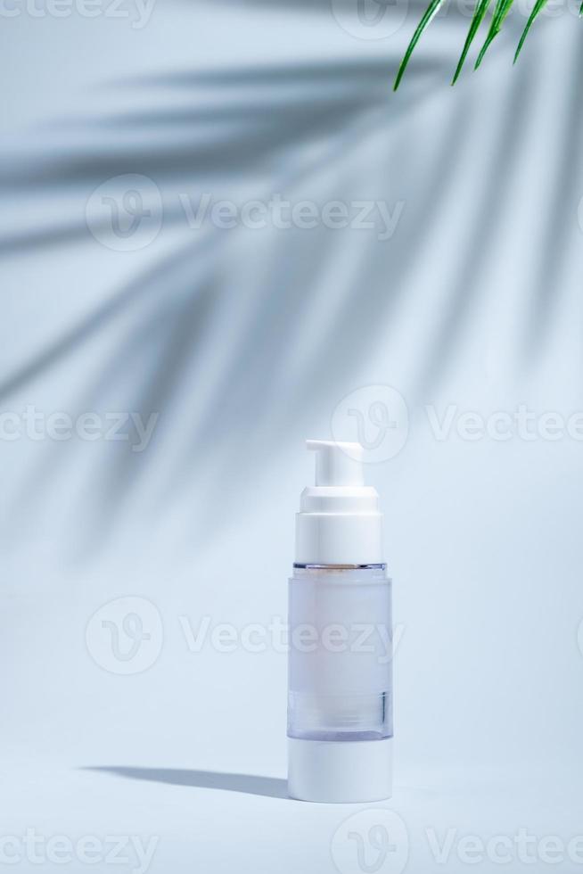 cosmetic and skin care package in a glass bottle on white background with hard or Harsh shadows and sunlight of leaves tree branch falling on wall. modern and minimal beauty product design photo