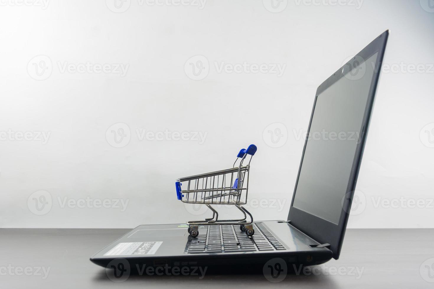 Computer notebook blank screen with shopping cart on wood table photo