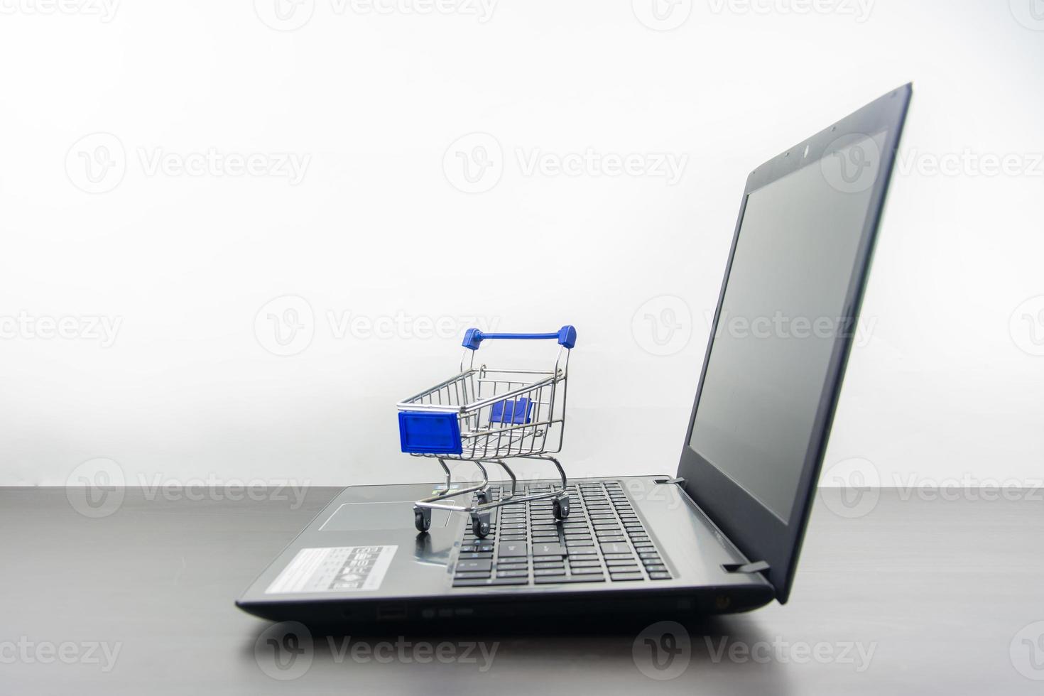 Computer notebook blank screen with shopping cart on wood table photo