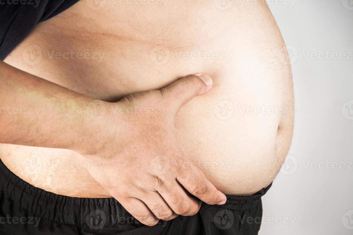 Overweight man body with hands touching belly fat photo