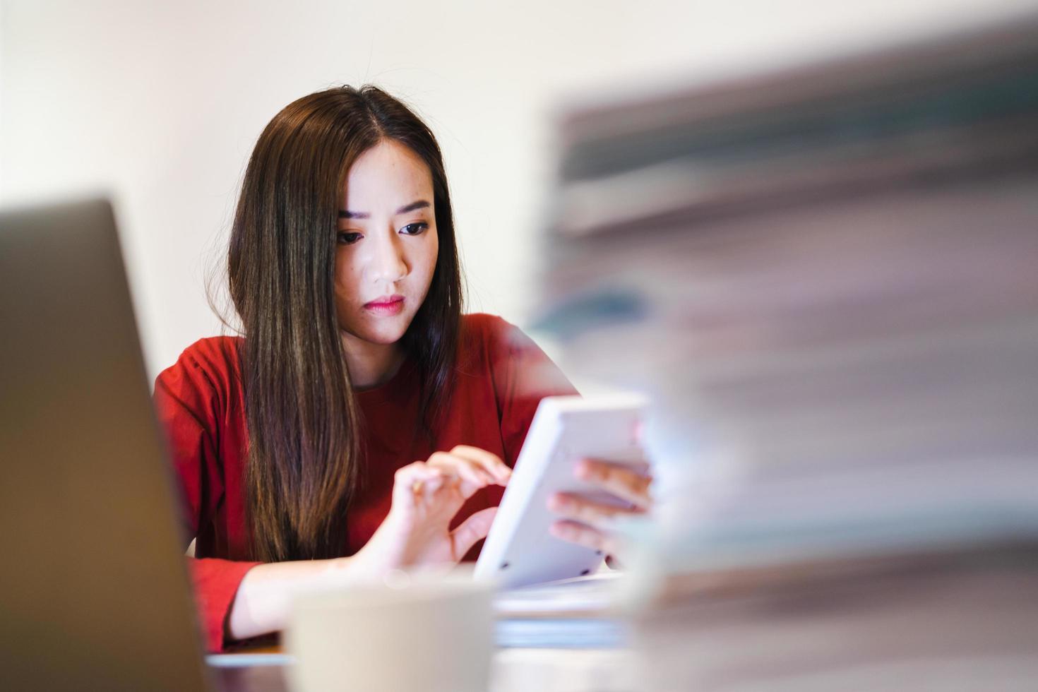 Asian Female Accountant using a calculator during overtime at night. Workaholic people photo