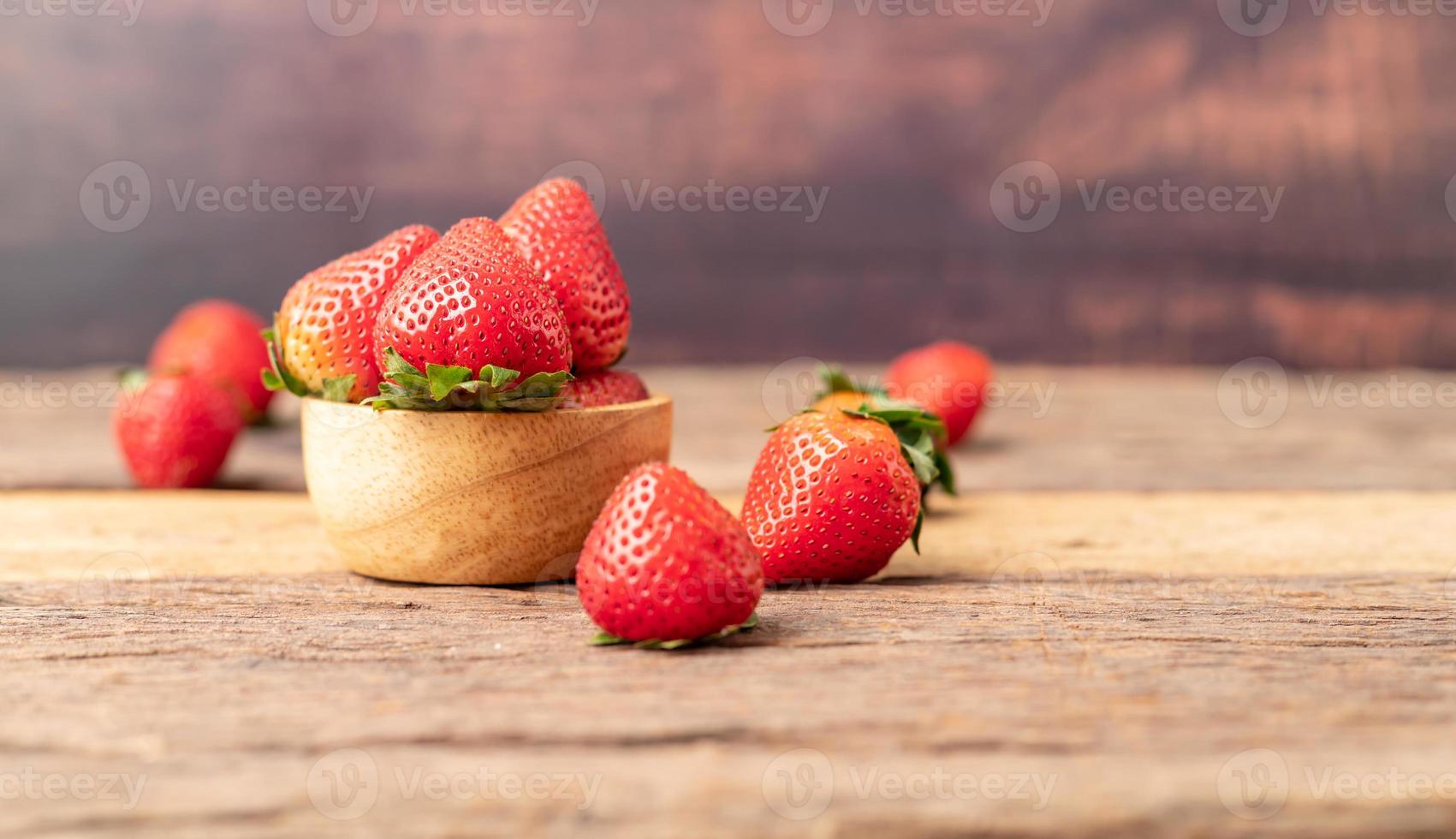 Freshness ripe strawberries are in a wooden bowl placed on the table photo