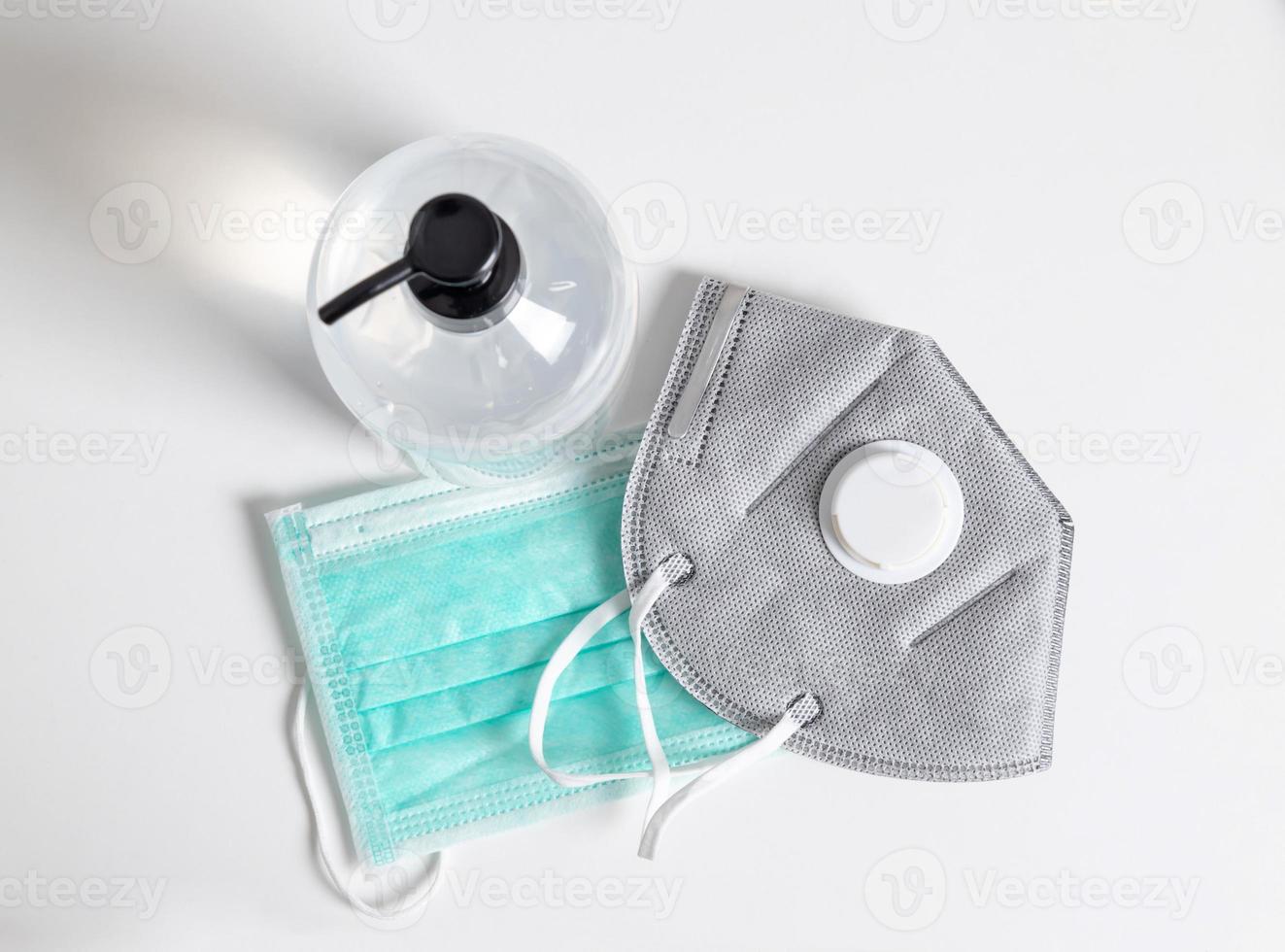 N95 and surgical masks with hand sanitizer gel on the white table photo