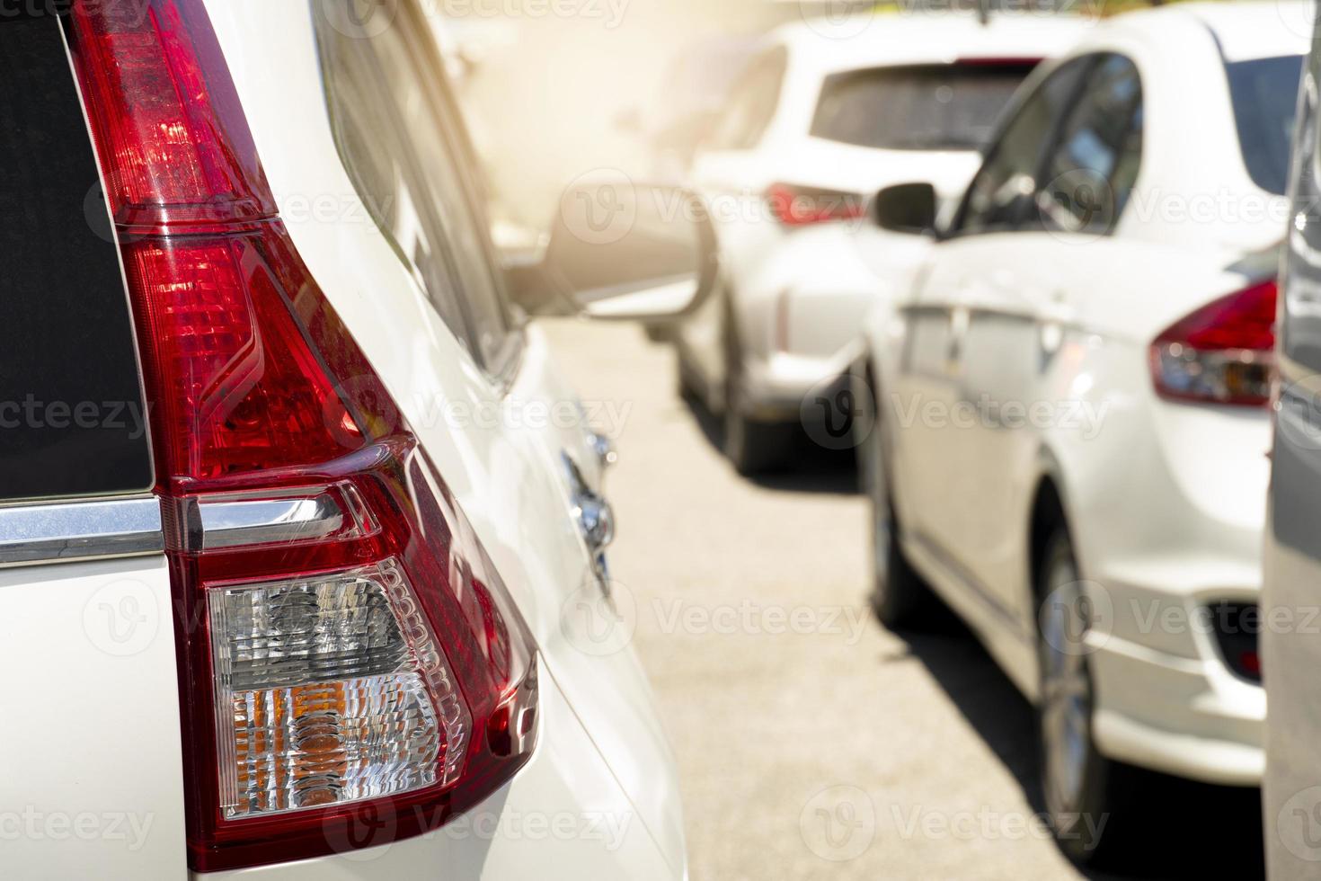 Rear side of white car on the asphalt road with bright light. Traffic jams in the city during the day. Queuing from many cars in front. photo