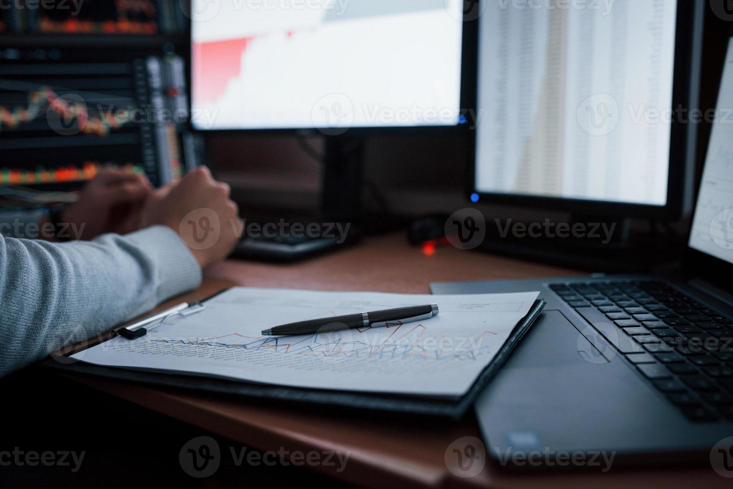 Close up view. Man working online in the office with multiple computer screens in index charts photo