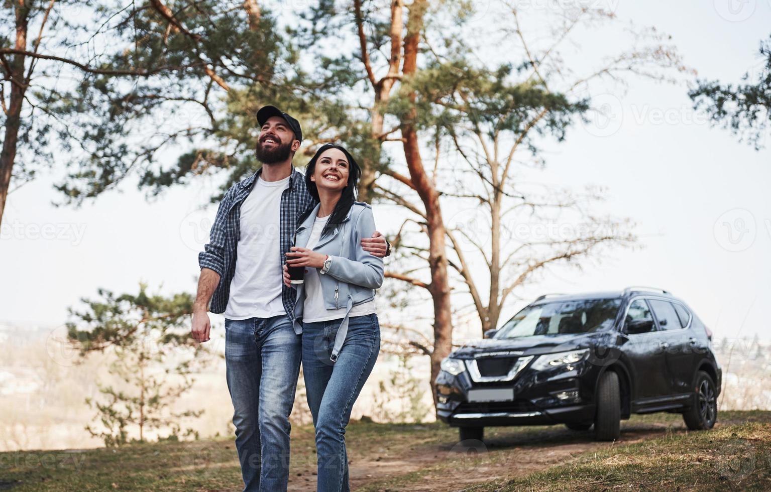 Peace and quiet. Embracing and enjoying the nature. Couple have arrived to the forest on their brand new black car photo