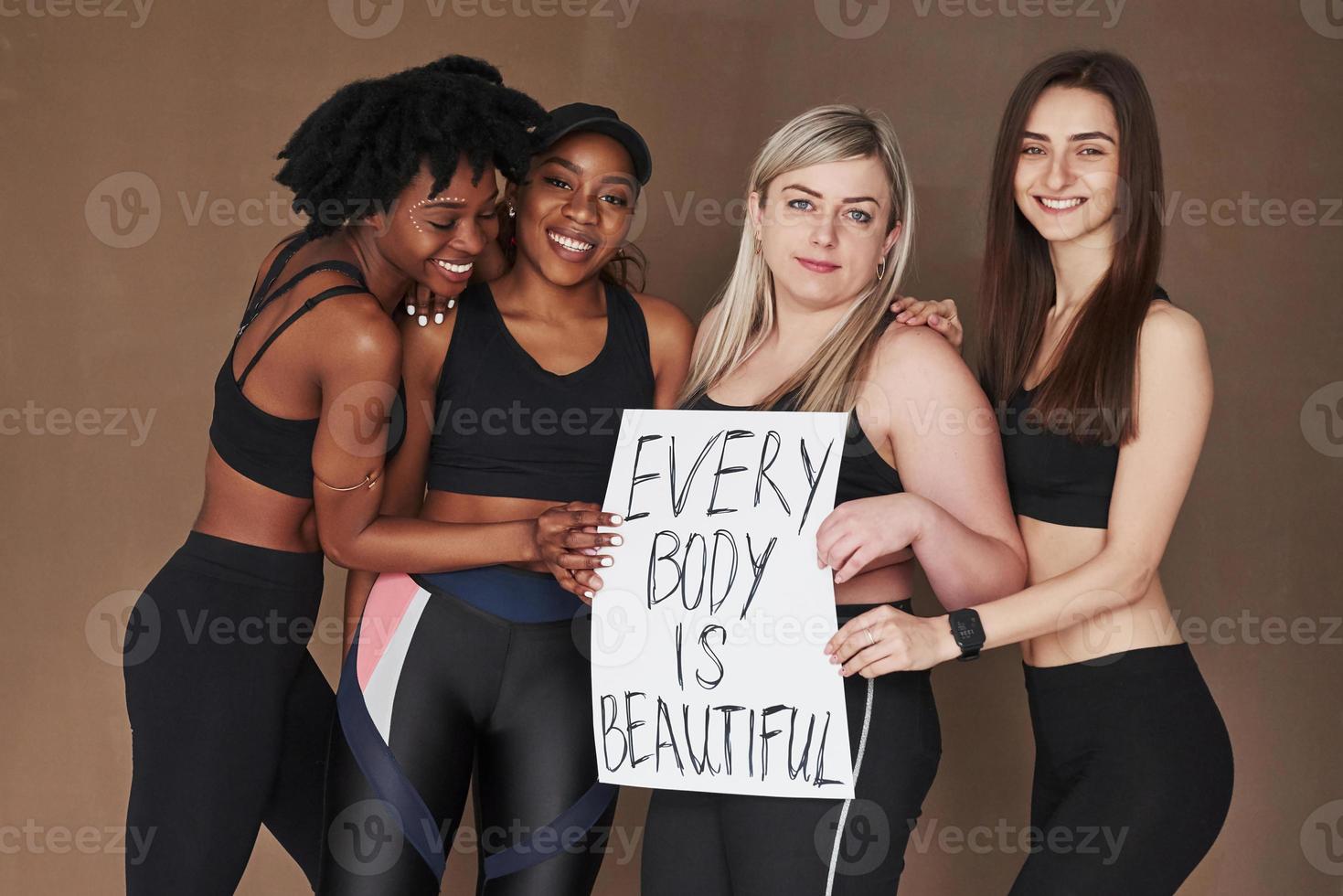no tengas miedo de ser tú mismo. grupo de mujeres multiétnicas de pie en el estudio con fondo marrón foto