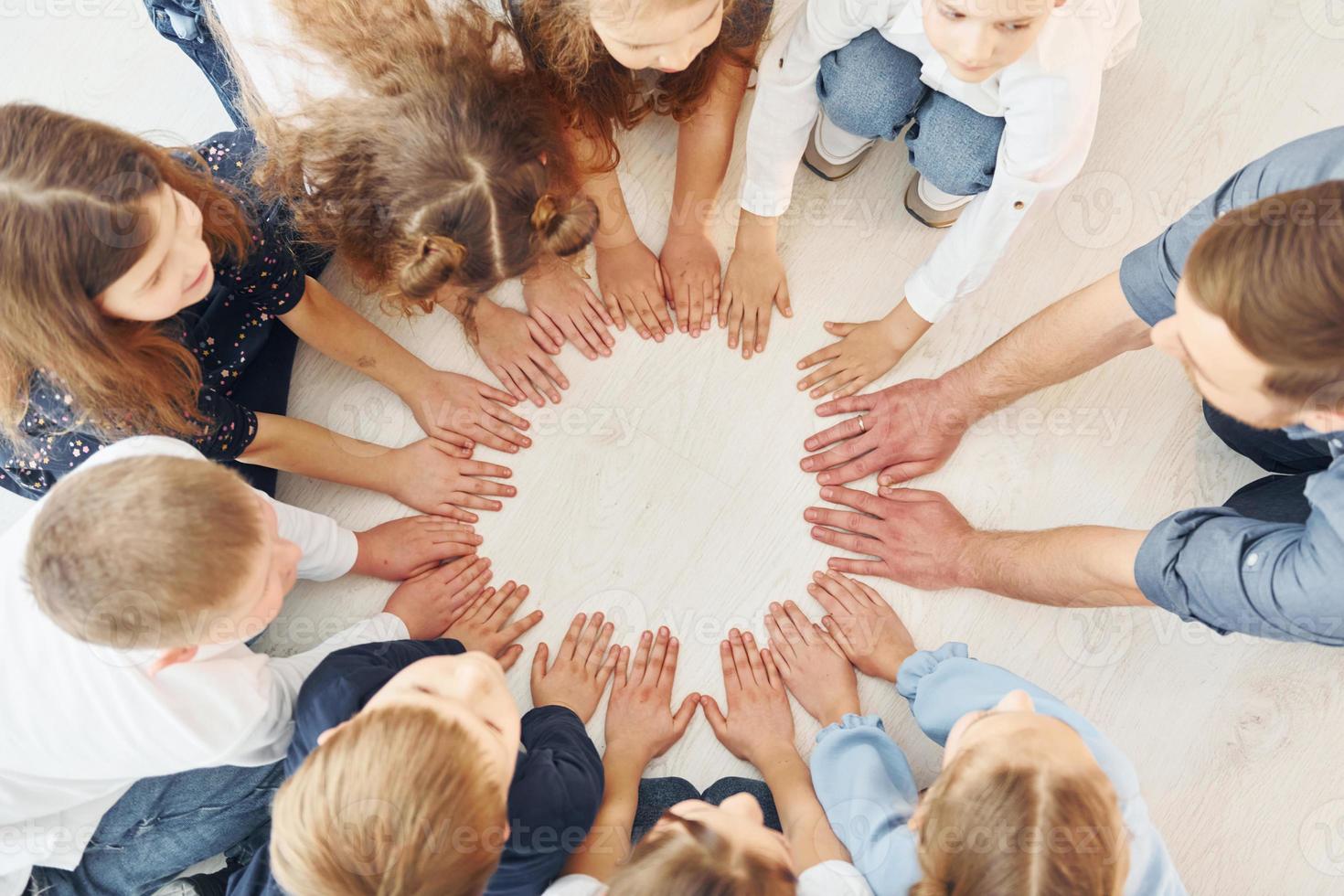 Top view. Man with his kids students in holding hands for success. Conception of education photo