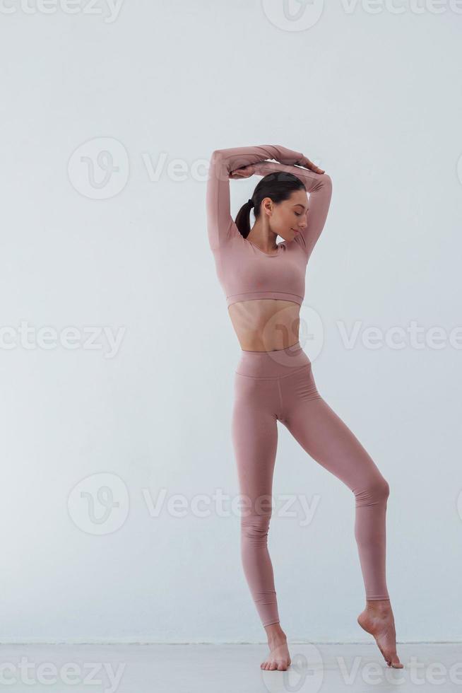 tipo de cuerpo flaco. mujer bonita caucásica haciendo ejercicios contra fondo blanco en el estudio foto