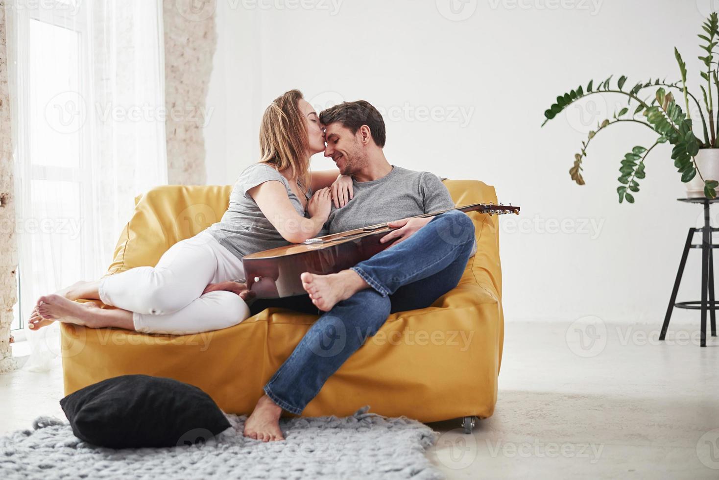 Thankful girlfriend gives a kiss. Happy couple relaxing on the yellow sofa in the living room of their new house photo