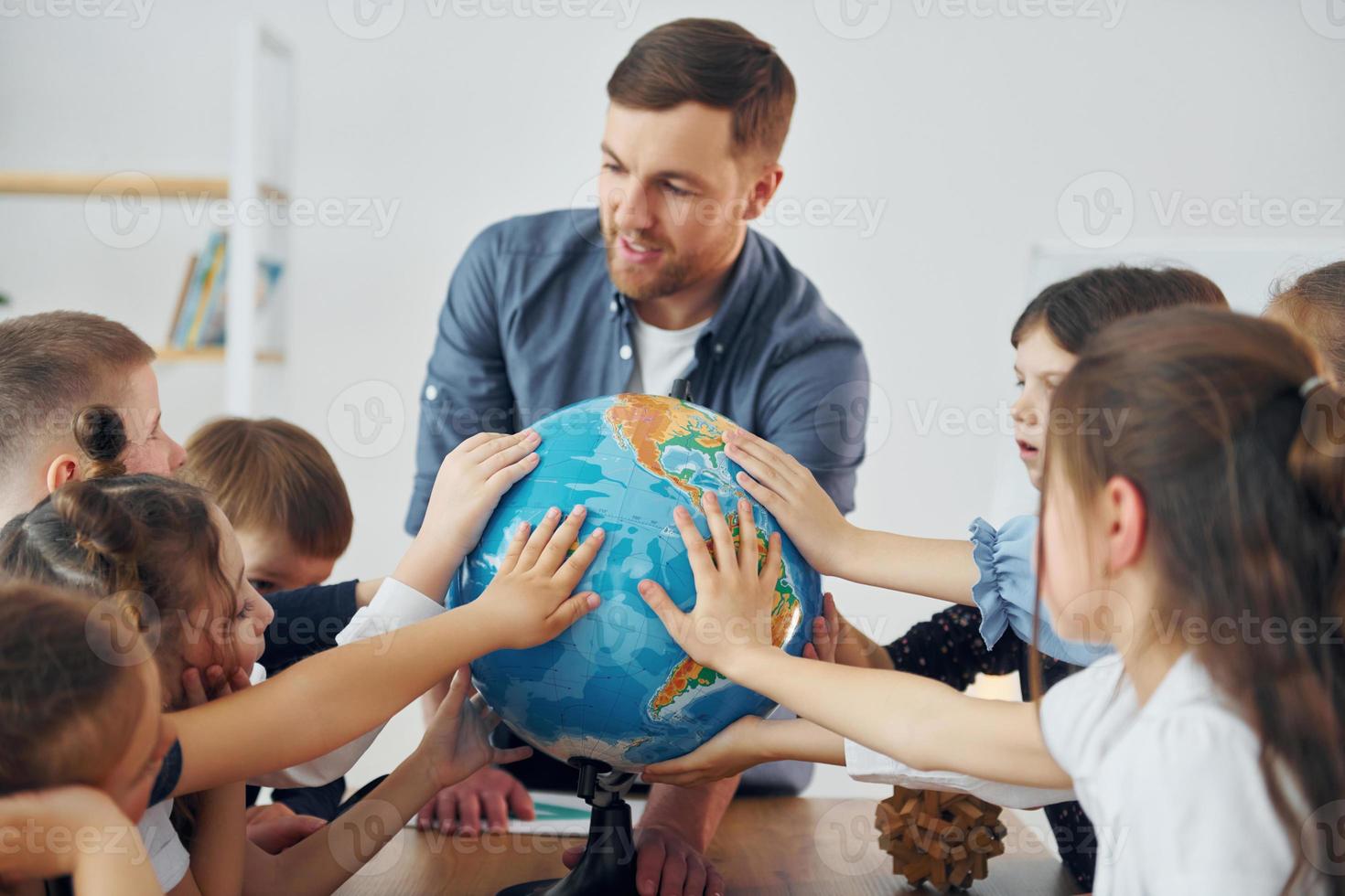 Touching the Earth globe. Group of children students in class at school with teacher photo