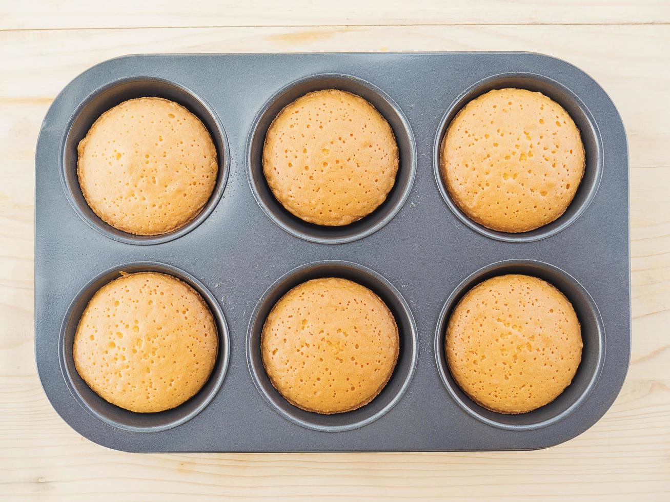 Muffin cake in the steel mold over white wooden background ready to be served photo