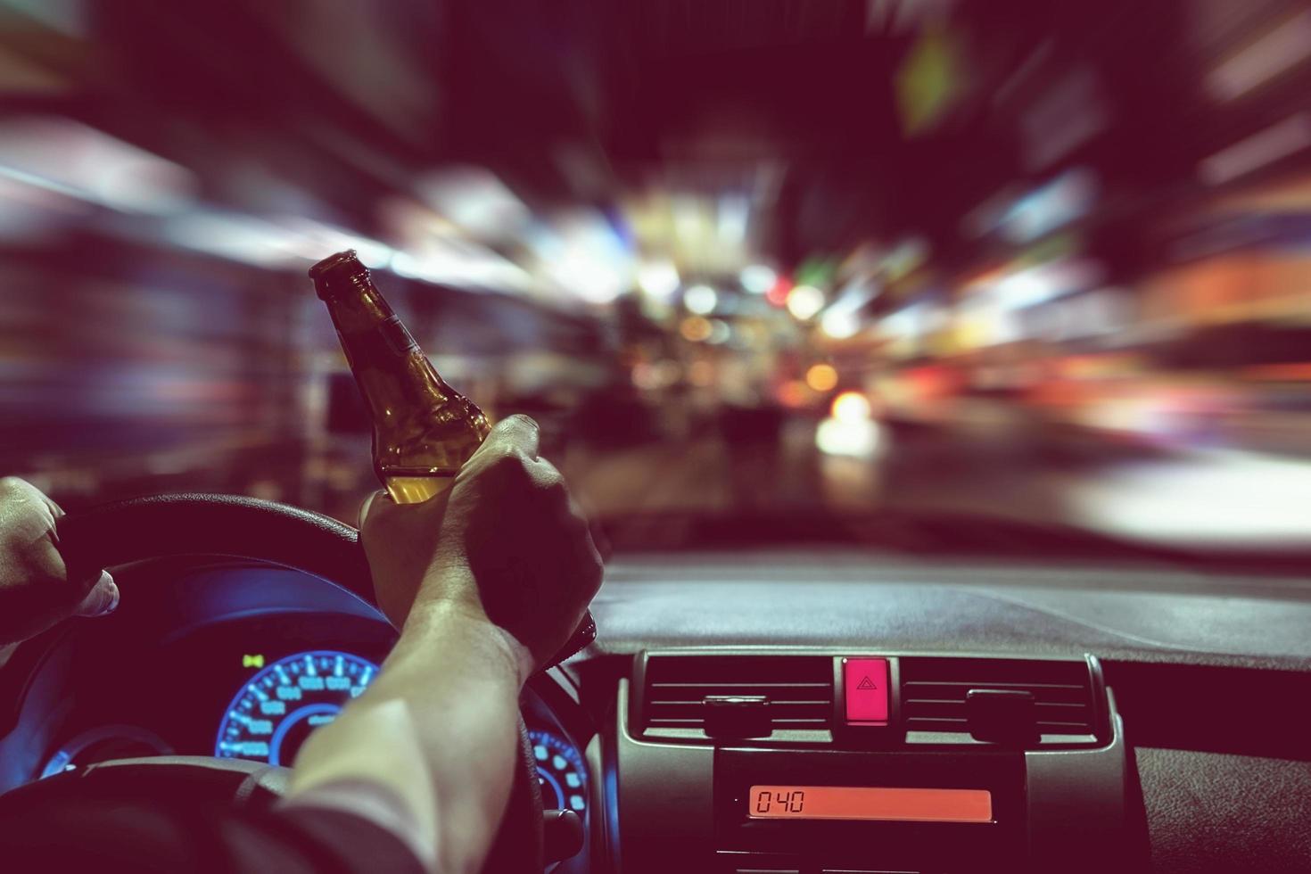 Man drink beer while driving at night in the city dangerously, left hand drive system photo