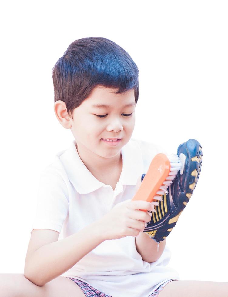 A boy is happily cleaning his shoe isolated on white background photo