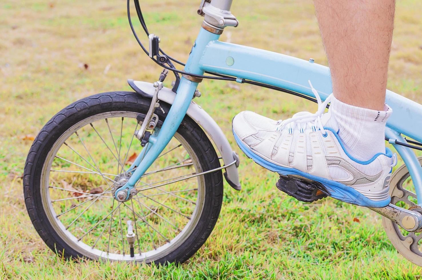 Closeup of lower part of man is riding bicycle. Photo is focused at a shoe.