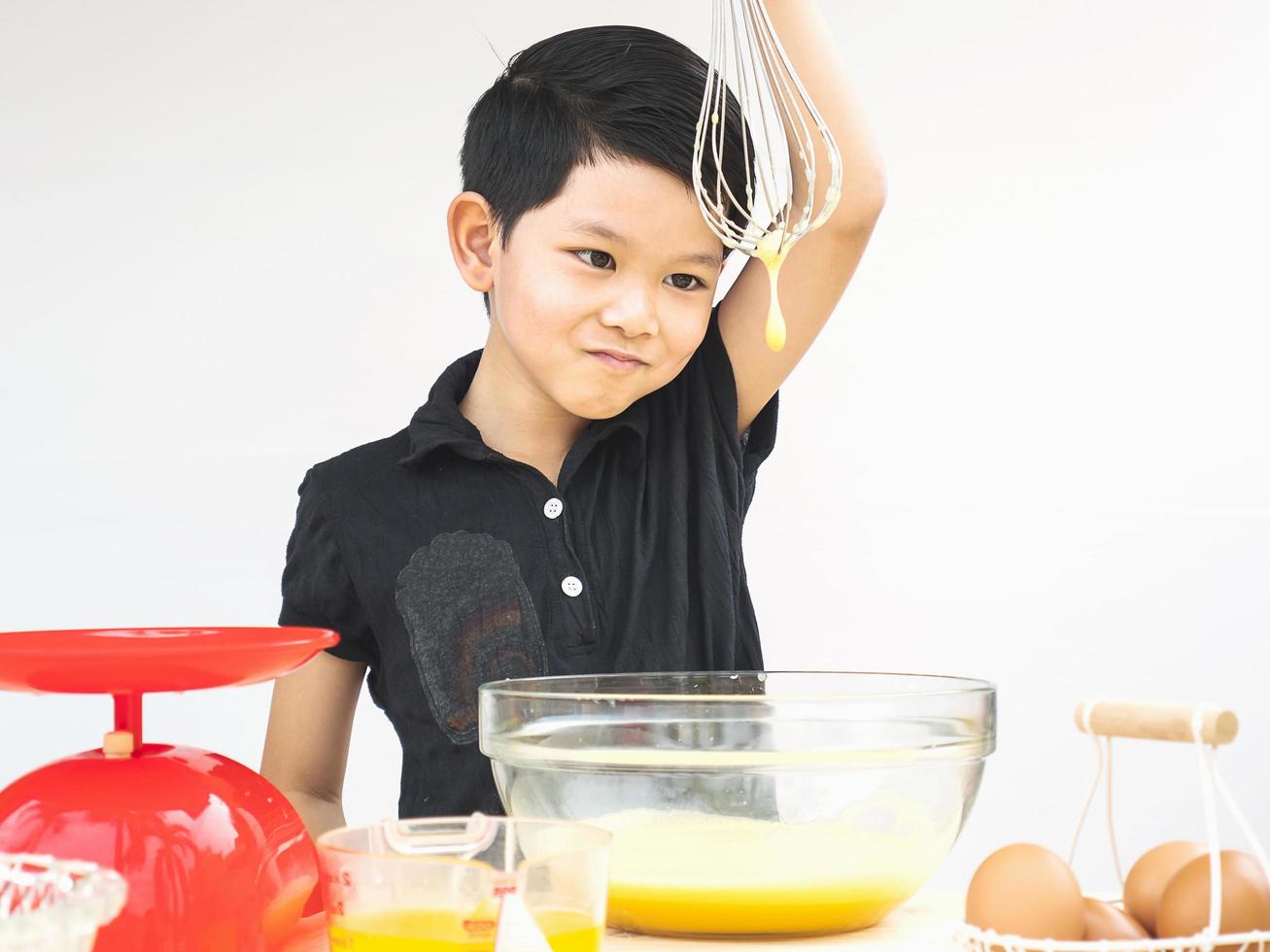 A boy is making cake. Photo is focused at his eyes.