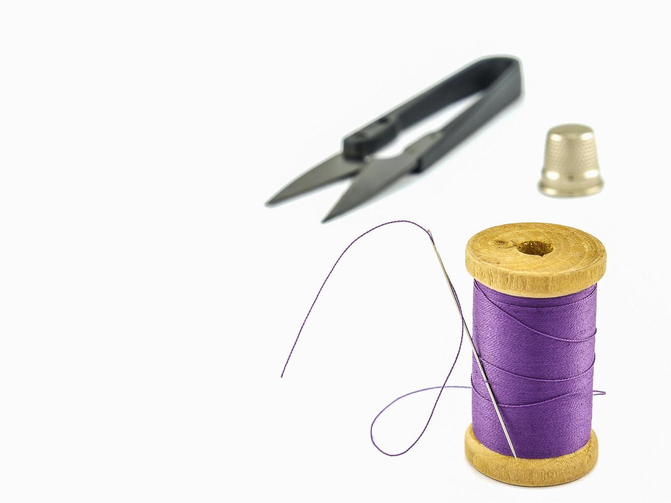 Thimble, needles, spools, scissors isolated over white background photo