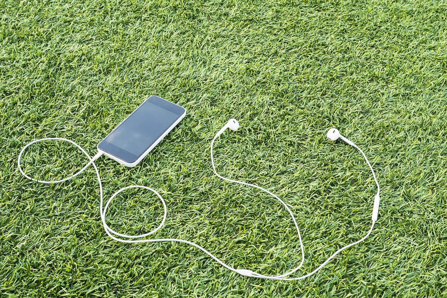 Mobile phone with head phone on green artificial grass photo