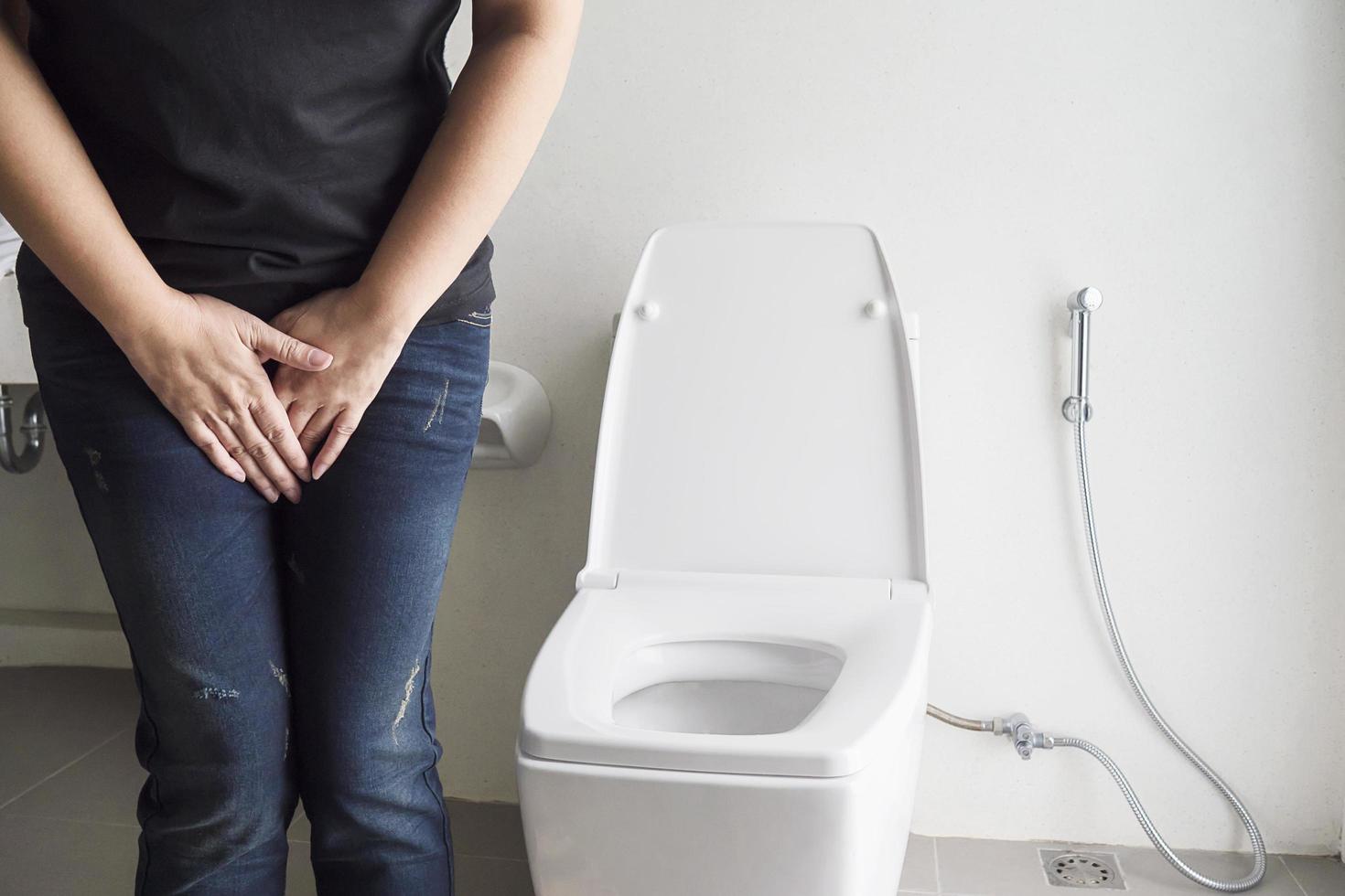 Woman holding hand near toilet bowl - health problem concept photo